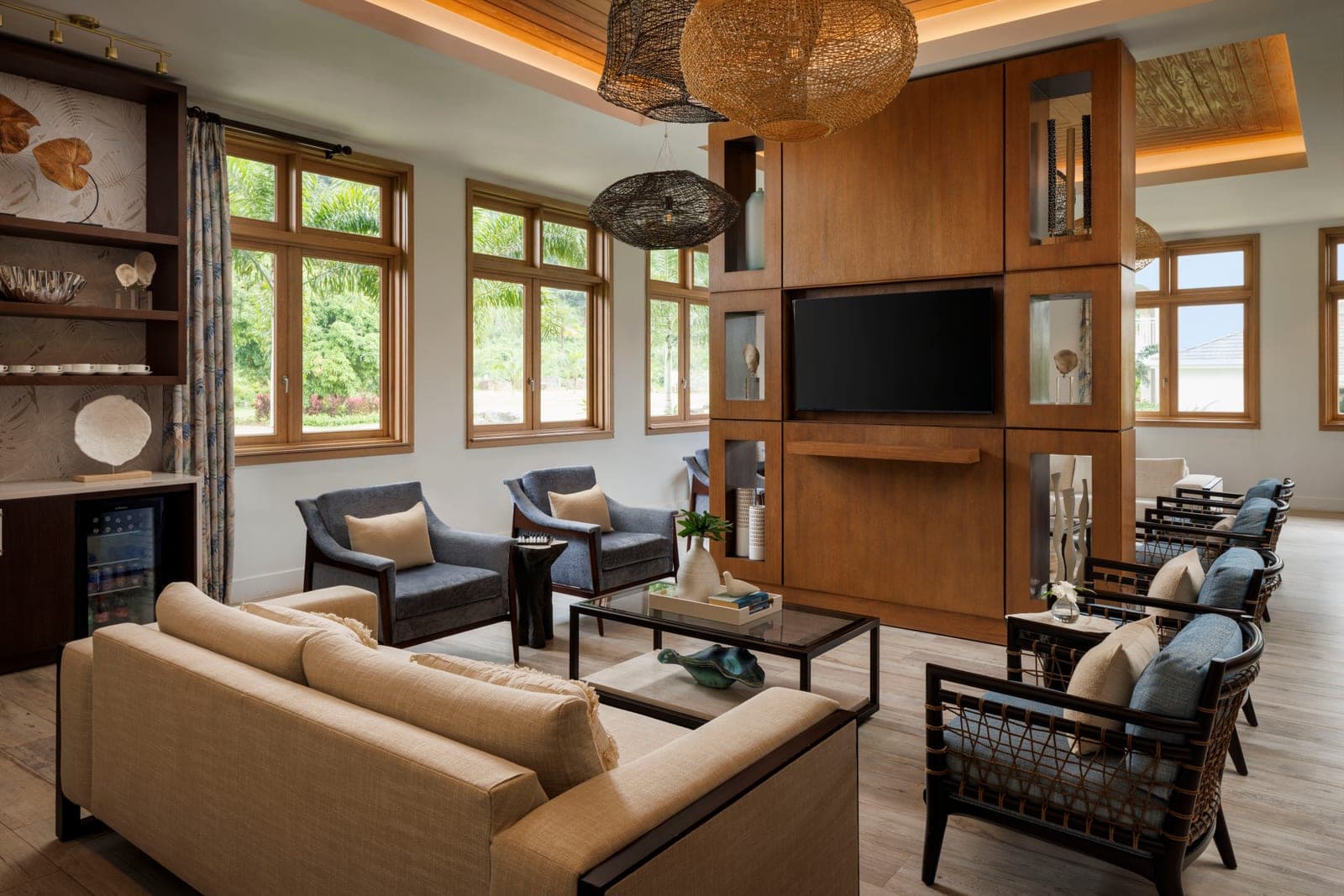 Lounge seating with a wall-mounted TV and woven pendant lights at Sandals Saint Vincent